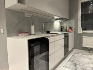 uma cozinha com armários brancos e uma máquina de lavar louça preta em Välkomsthörnet em Estocolmo