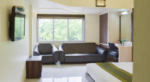 um quarto de hotel com um sofá e uma televisão em Hotel Palliate em Ahmedabad
