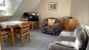 ein Wohnzimmer mit einer Couch und einem Sessel und einem Fernseher in der Unterkunft Cafe Gaubenhaus in Bad Fallingbostel