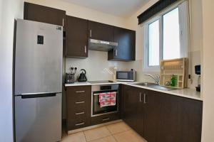 uma cozinha com um frigorífico de aço inoxidável e armários castanhos em Mythical Sands Resort - Swahili Apartment em Protaras