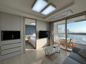 1 dormitorio y sala de estar con sofá y TV. en Landmark Songdo Stay, en Incheon