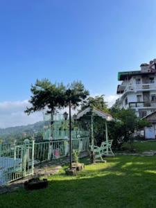 un parque con un parque infantil con un árbol y un edificio en The Gingko Eyrie , Kalimpong en Kalimpong