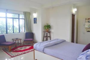 a bedroom with a bed and two chairs and a window at The Gingko Eyrie , Kalimpong in Kalimpong