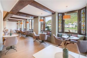 un restaurant avec des tables, des chaises et des fenêtres dans l'établissement Hotel Weinhof, à Cochem