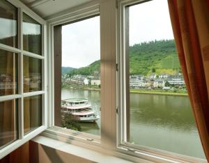 ein Fenster mit Blick auf einen Fluss und ein Boot in der Unterkunft Hotel Weinhof in Cochem