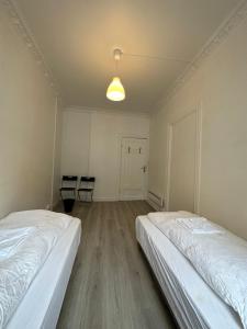 two beds in an empty room with two chairs at Concept Exodo Apartments in Oslo