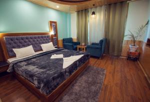 The Forest Pinnacle & Café, Manali في مانالي: غرفة نوم بسرير كبير وكرسيين
