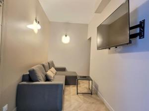 een woonkamer met een bank en een flatscreen-tv bij Appart Hotel Cinéma Perpignan in Perpignan