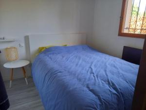 ein Schlafzimmer mit einem blauen Bett und einem Stuhl in der Unterkunft Petite maison de charme à 1km du lac de Sanguinet et 20min d'Arcachon in Sanguinet