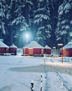 a snow covered field with some buildings and trees at The Glamping Spot Kalam in Kalām