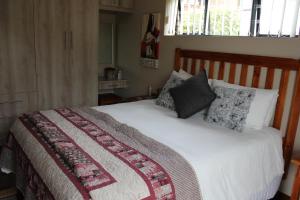 1 dormitorio con 1 cama con manta y almohadas en Traveller's Rest, Reebok en Mossel Bay