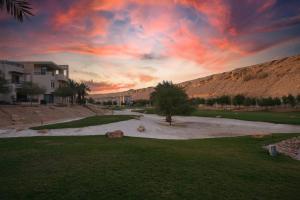 a sunset over a golf course with a house and a tree at Obeir Resident Hotel - فندق اوبير السكني in Riyadh