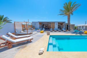 een zwembad met ligstoelen en een huis bij White and Grey in Mykonos-stad