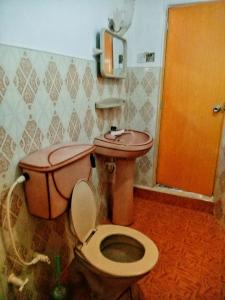 ein Badezimmer mit einem rosa WC und einer braunen Tür in der Unterkunft Royal Princess Holiday Inn in Alutgama