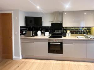 a kitchen with white cabinets and a stove top oven at Luxury Apartment with King-size Bed in Central Cambridge - Walk to Station and City Centre in Cambridge