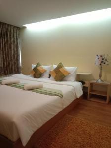 um quarto com uma grande cama branca com almofadas em NOP PLACE BANGNA em Ban Bang Phrao
