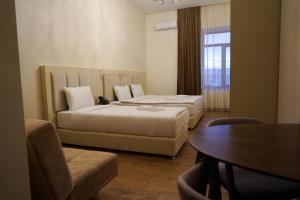 um quarto de hotel com duas camas e uma mesa e uma mesa em KUMA Hotel Gyumri em Guiumri