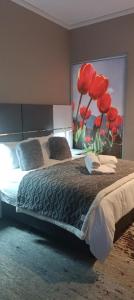 Schlafzimmer mit einem Bett mit einem roten Tulpenbild in der Unterkunft Menlyn Maine Trilogy Apartment 1518 in Pretoria