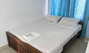 Una cama con sábanas blancas y una báscula. en FabExpress Aabriz Residency, en Ernakulam