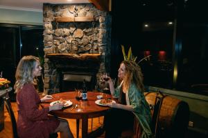duas mulheres sentadas numa mesa com copos de vinho em Eagles Nest Retreat em West Kentish