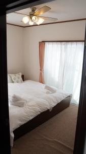 - une chambre avec un lit, un ventilateur de plafond et une fenêtre dans l'établissement Casa Hakuba, à Hakuba