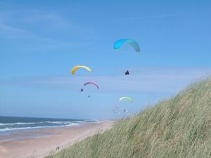 een groep vliegers die over een strand vliegen bij Zomerhuisje Wijk aan Zee in Wijk aan Zee