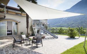 un patio con sillas y una sombrilla blanca en Appartamenti Al Vigneto, en Dro