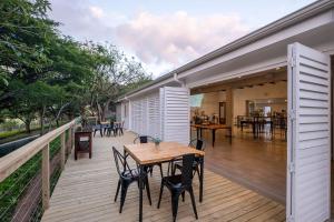 eine Holzterrasse mit einem Tisch und Stühlen darauf in der Unterkunft The Lodge at Prince's Grant Coastal Golf Estate in Blythedale