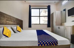 una camera da letto con un grande letto con cuscini gialli e blu di OYO Hotel Crown Plaza a Rudrapur