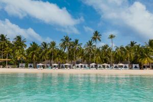 a beach with umbrellas and palm trees at One&Only Reethi Rah in Reethi Rah