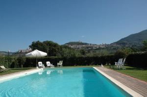 a swimming pool with two chairs and an umbrella at Il Podere del Falco in Assisi