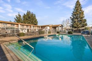 a swimming pool in front of a building with a tree at Heritage Inn Express Chico in Chico