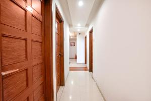 a hallway with a wooden door and a white tile floor at FabHotel Shanti Sadan Near Ellisbridge in Ahmedabad