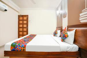 a bedroom with a white bed with a wooden headboard at FabHotel Shanti Sadan Near Ellisbridge in Ahmedabad