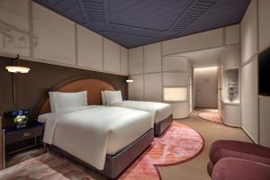 a bedroom with two beds and a couch at Hotel Indigo Wuxi Taihu New City in Wuxi