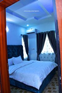 a bedroom with a large bed and two windows at Tegsview Apartments, Ughelli in Ughelli