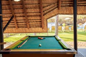 una mesa de billar en un pabellón con piscina en Waterberry Hill, en Hazyview