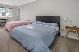 オークランドにある7BR 3BH Beach Escape. 2 min to Browns Bay Beachのテーブルと机のある部屋にベッドが2つある