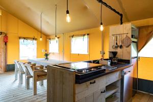 a kitchen with a counter and a table with chairs at Luxe Safaritent 6 persoons op Camping Rijsterbos in Rijs