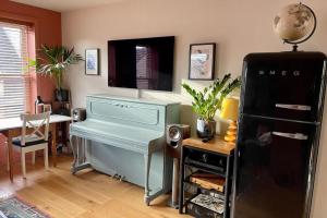 a room with a piano and a desk and a refrigerator at Charming and Spacious 2 Bed Near Kensal Green Tube in London