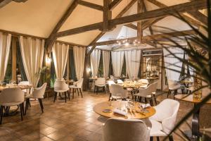 un comedor con mesas, sillas y ventanas en Moulin de Cambelong- Emilie & Thomas, en Conques-en-Rouergue