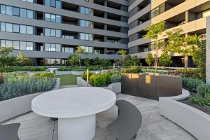 a patio with a white table and benches and a building at Zi apartments - with Balcony, Bayview, Sauna and Pool in Melbourne