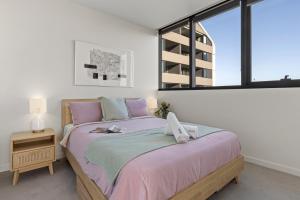 una camera da letto con un letto con lenzuola rosa e una finestra di Zi apartments - with Balcony, Bayview, Sauna and Pool a Melbourne
