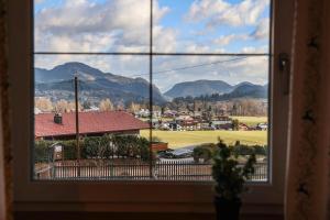 a window with a view of a town and mountains at Ferienwohnung Söldenköpfl-Blick in Schönau am Königssee