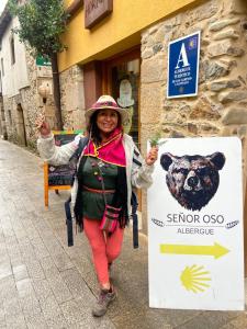 una mujer de pie junto a un cartel con un oso en SEÑOR OSO, en Molinaseca