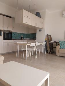 a kitchen with white cabinets and white tables and chairs at Amazing waterfront Apartment in Hurghada