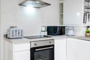 a white kitchen with a microwave and a stove at Modern 2 Bedroom Flat - Short Walk From The Station in Cambridge