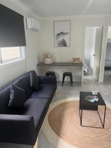 a living room with a black couch and a table at Batemans Bay North Bush Cottages in Benandarah