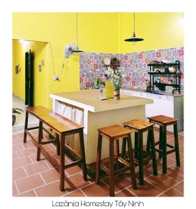 a kitchen with a counter with four stools and a table at Lazánia homestay Đất Thánh-số 8a hẻm số 3 Phạm Văn Xuyên in Tây Ninh