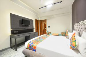 Dormitorio con cama, escritorio y TV en FabHotel Naina Residency en Rāiwāla